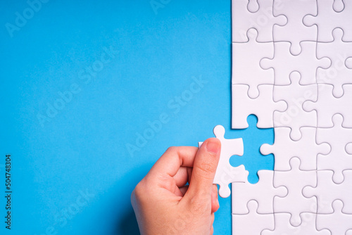 hand jigsaw puzzle pattern missing piece White jigsaw puzzle pattern top view to express alliance union team working solution success problem. Business assemble metaphor or puzzles game challenge. photo