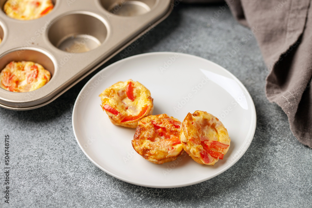 Egg muffins or bites with vegetables and micro greens in a plate on a gray background Egg muffins or bites with vegetables and micro greens in a plate on a gray background