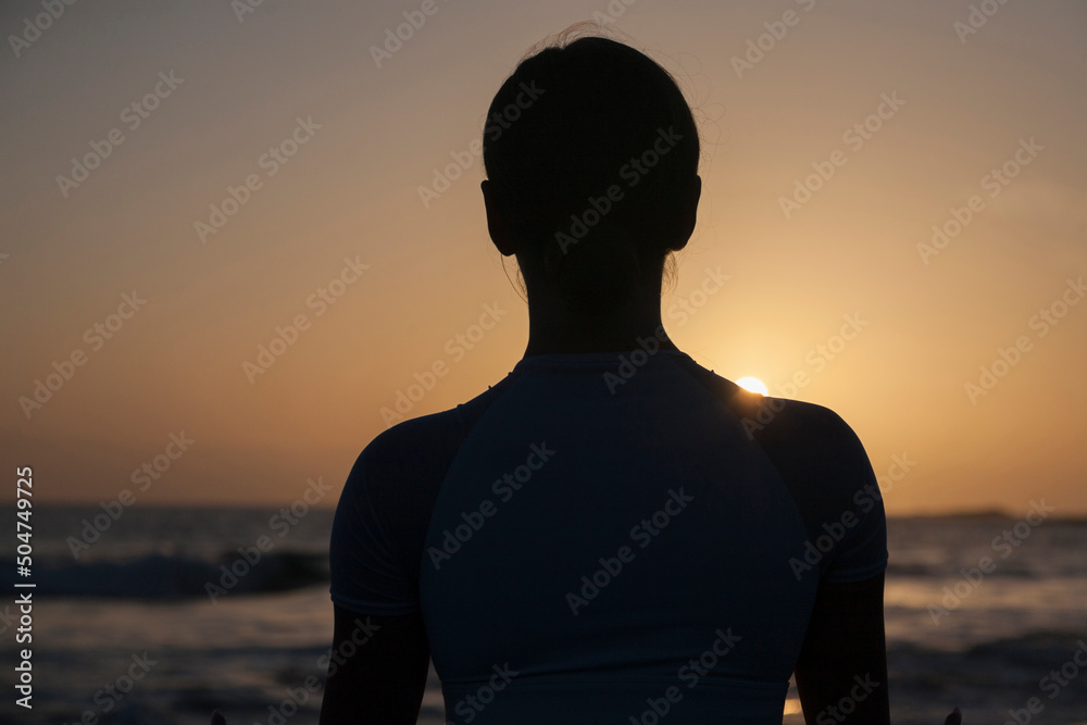 Young woman meditation in a yoga pose at the beach on sunset. Silhouette of woman close up. Meditation and relax. Young woman meditation in a yoga pose at the beach on sunset. Silhouette of woman close up. Meditation and relax.