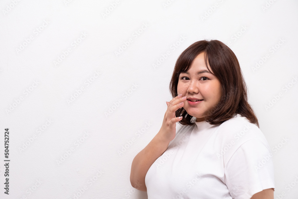 Young beautiful Asian oversize women smile with positive emotion, feeling happy and proud with her body size. Portrait shot on white background with copy space. Young beautiful Asian oversize women smile with positive emotion, feeling happy and proud with her body size. Portrait shot on white background with copy space.