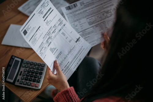 Close-up of female hands with pay slips, utility bills, account statements, payment receipts. A woman makes a count of household, family expenses