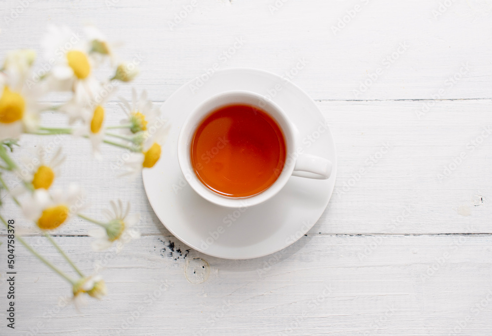 Chamomile flowers and white cup of tea. Alternative tea and medicine concept. Chamomile flowers and white cup of tea. Alternative tea and medicine concept.