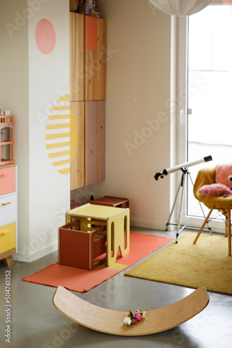 Kids play room, nobody. Nice sunny bright interior at home. Play and rest and create, store things and climb on the wall, balance Board Curvy Rocker Board used for motor physical development photo