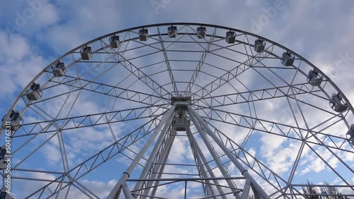 Ferris wheel on a background of blue sky and clouds. Entertainment park
