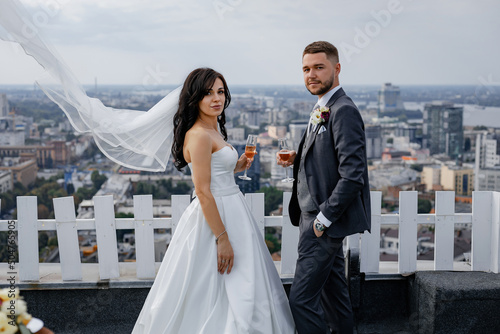 City view. High skyscrapers and a bridge across the river. Business center. Stylish wedding couple on the roof of the house. Beautiful view