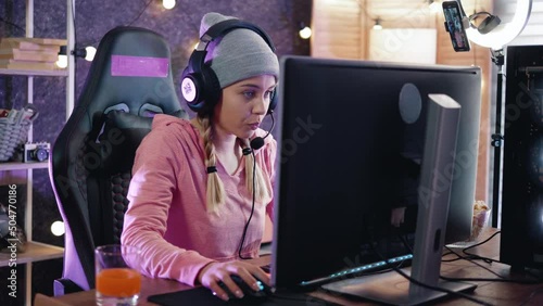 Excited streamer in her room playing online video games with friends online. Female teenager is looking forward to winning by playing an online video game at home photo