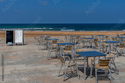 beachfront restaurant with empty chairs and tables and menu boards and no customers