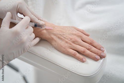 Woman receiving hand rejuvenation injection in beauty salon