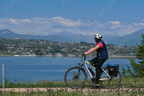 Ride on an electric bike. Man driving on an electric bike along Lake Garda in Italy. Man walk in nature.