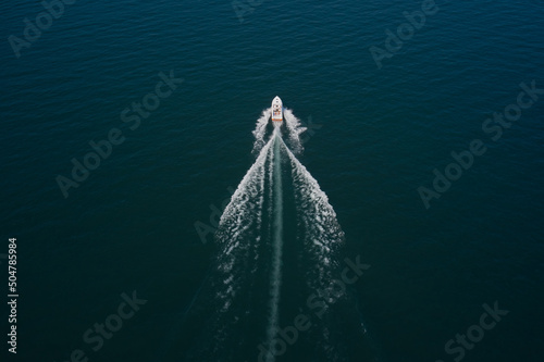 Aerial view luxury motor boat. Drone view of a boat sailing. Motor boat in the sea. Top view of a white boat sailing to the blue sea.