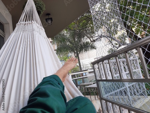 Homem descansando na rede na varanda - Man resting in hammock on balcony photo