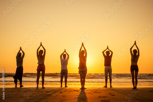 six health people in stand hatha position with hand up raced and breath full chest in Goa India beach at sunset