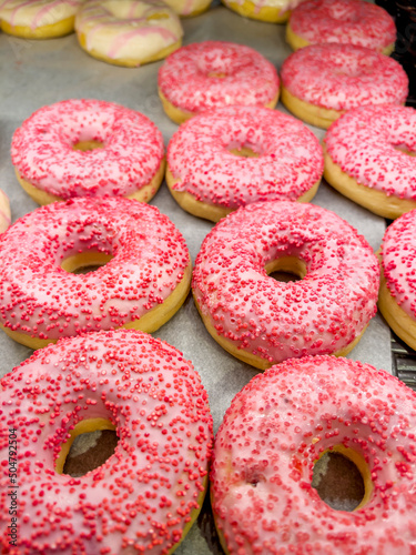 Assorted pink donuts in bakery shop