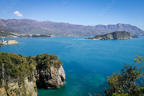 Scenic landscape of Adriatic sea coast in Montenegro, Budva area. Turquoise water, Sveti Nikola (Hawaii) Island and mountains in background. 