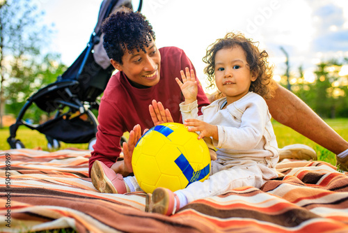 latin hispanic father and multicultural race little girl spending vacation outdoor sit meadow