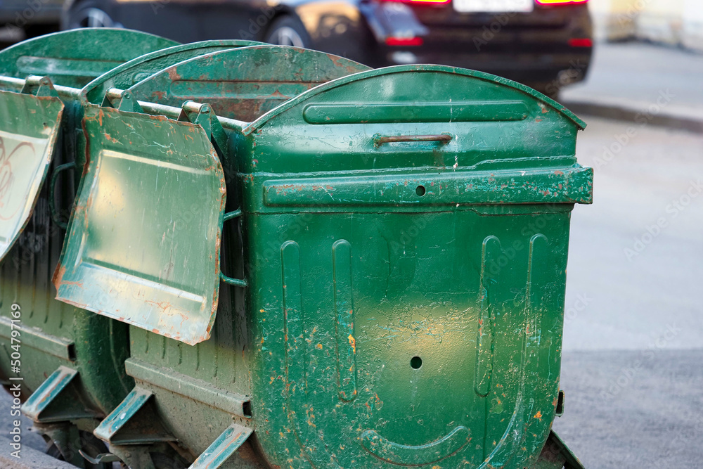Green metal garbage containers with wheels in city street
