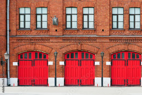 Fire station, an old historic brick building with red gates. Facade of an old fire department building