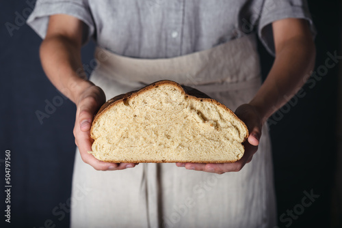 Female hands holding homemade fresh baked half bread. Gluten free, healthy diet concept. Dark rustic style. 