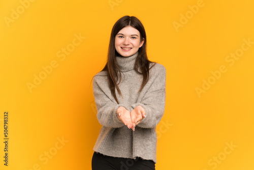 Young Ukrainian girl isolated on yellow background holding copyspace imaginary on the palm to insert an ad © luismolinero