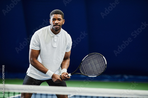 Front view portrait of handsome black sportsman playing tennis at indoor court, copy space © Seventyfour