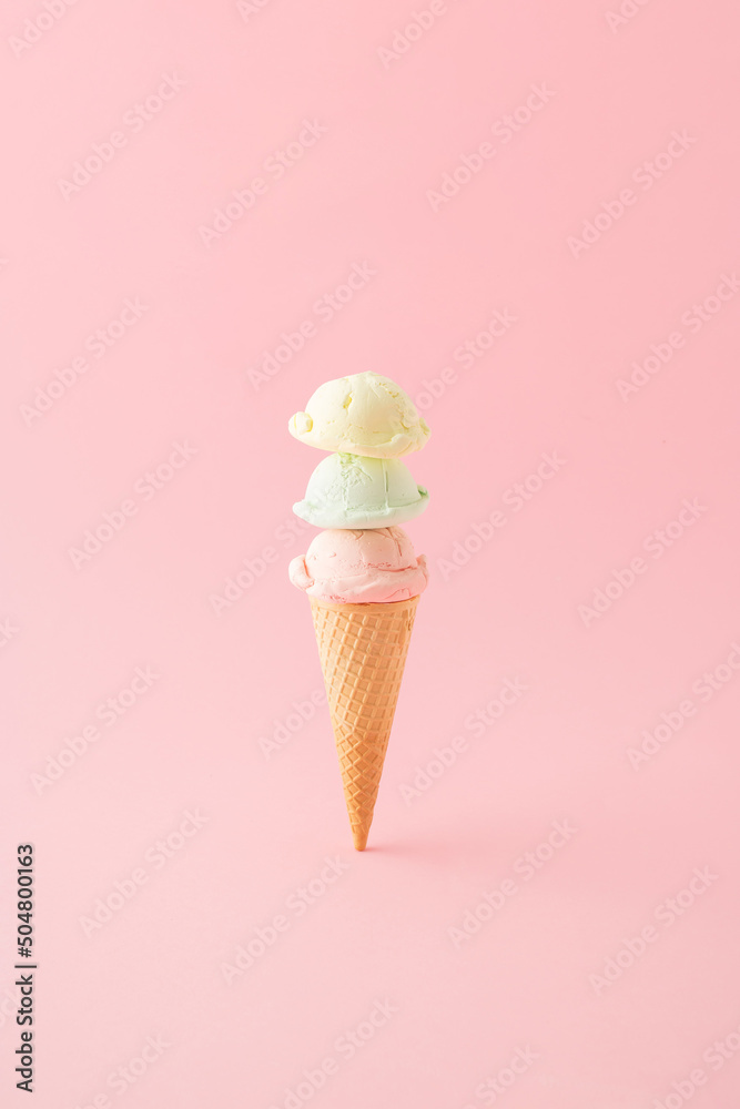 Ice cream with three scoops in a cone placed vertically on pink background. Minimal summer concept. Ice cream with three scoops in a cone placed vertically on pink background. Minimal summer concept.