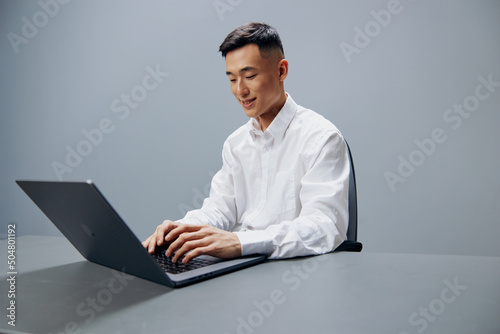 Asian man working on a laptop sitting at a table in the office Lifestyle