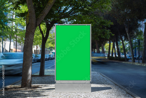 Empty billboard with a green screen for advertising on the street with moving cars