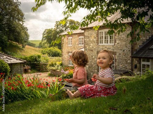 Little siblings girl and boy are eating fresh watermelon on a sunny day on her summer holidays at the countryside in a cottage in England