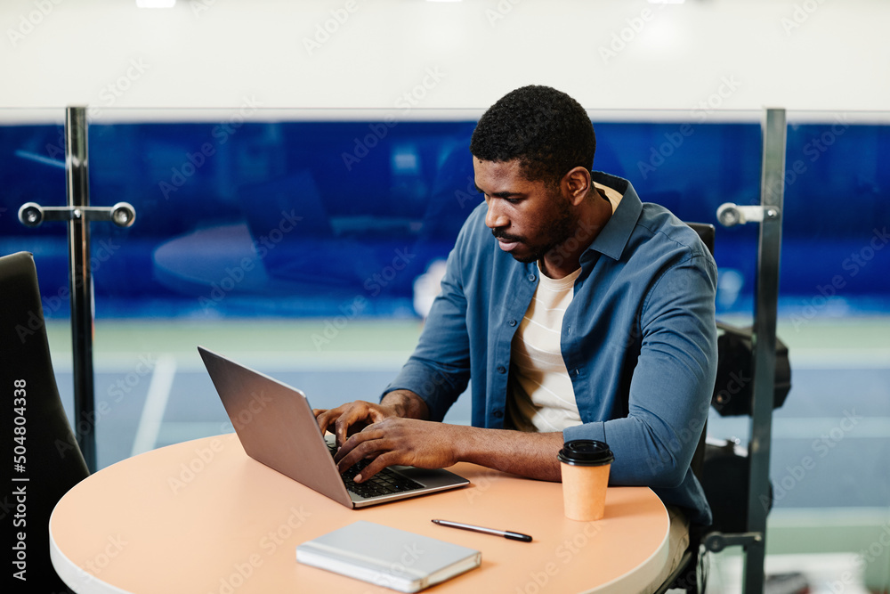Vibrant portrait of handsome black man using laptop in sports training center, copy space Vibrant portrait of handsome black man using laptop in sports training center, copy space