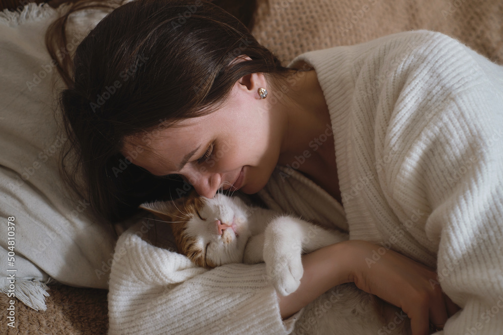young woman holding cute ginger cat with green eyes. Female hugging her cute short hair kitty in bedroom. Copy space, close up. Adorable domestic pet concept. young woman holding cute ginger cat with green eyes. Female hugging her cute short hair kitty in bedroom. Copy space, close up. Adorable domestic pet concept.