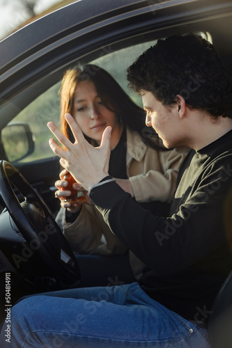 a young beautiful girl quarrels with her boyfriend who wants to drink alcohol while driving a car, alcohol dependence and codependency photo