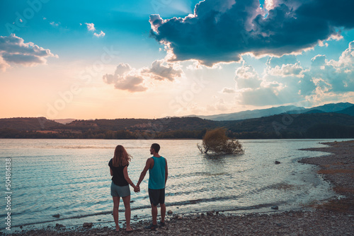 Young Attractive Couple holding hands in a Beautiful Lake in summer during sunset. Discovery Travel love Destination Concept. photo