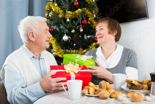 Elderly husband and wife exchange holiday gifts for Christmas and New Year