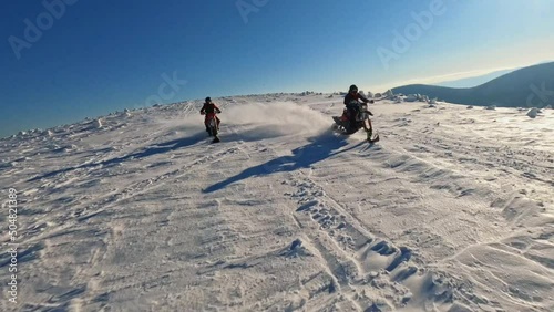 Beautiful aerial top view in mountains, two guys on snowmobile jumps and rides in the winter at sunlight