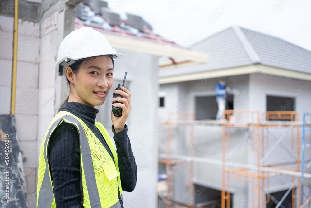 Asian Woman engineer foreman architect worker with hard hat.working on construction site communication with walkie talkie.Beautiful thai female construction worker in Project site PPE safety first. Asian Woman engineer foreman architect worker with hard hat.working on construction site communication with walkie talkie.Beautiful thai female construction worker in Project site PPE safety first.