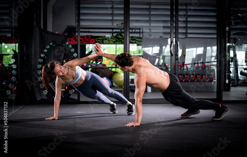 Fototapet Sport fitness woman and guy trainer in sportswear exercise doing cheer hand show happiness and push ups as part of CrossFit bodybuilding training at gym is Muscular body building in fitness lifestyle