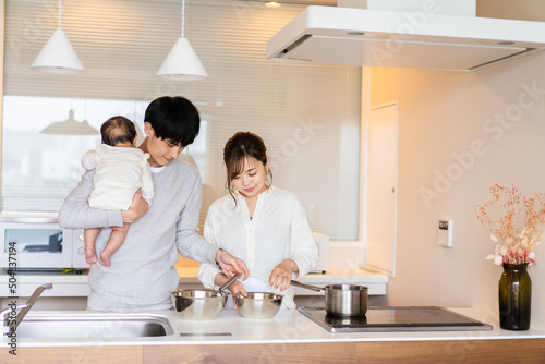 キッチンで料理をするお母さんとお父さんと赤ちゃん