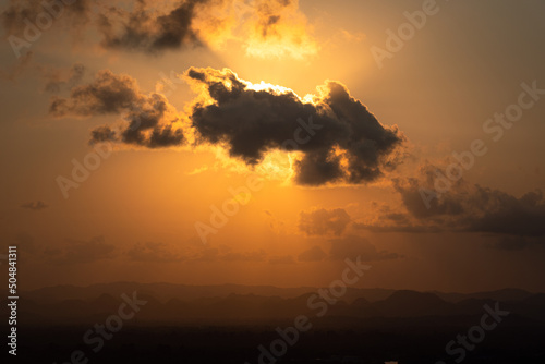 Orange sunlight behind the cloud on dramatic sky. Nature abstract scene, high contrast ration photo with dark and shadow area.