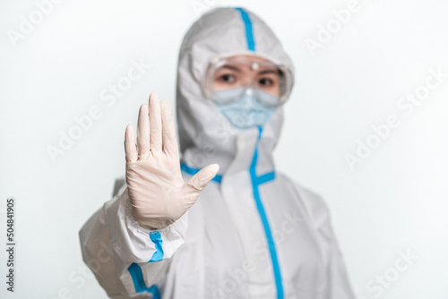 Doctor or nurse wearing protective suit and mask showing stop gesture on the white background.