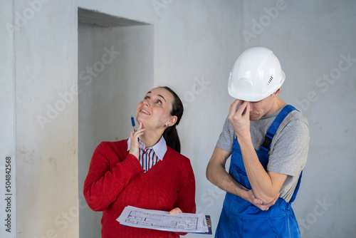 Slika na platnu Female Client and Male Contractor Discussing Blueprints and Renovation Work on a
