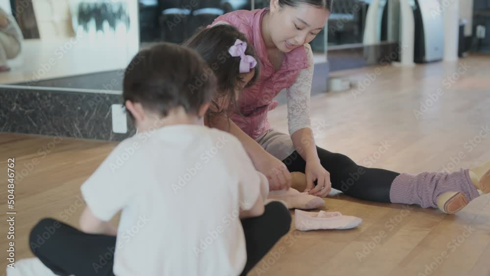 子供たちがバレエシューズを履く手伝いをするバレエ講師 子供たちがバレエシューズを履く手伝いをするバレエ講師