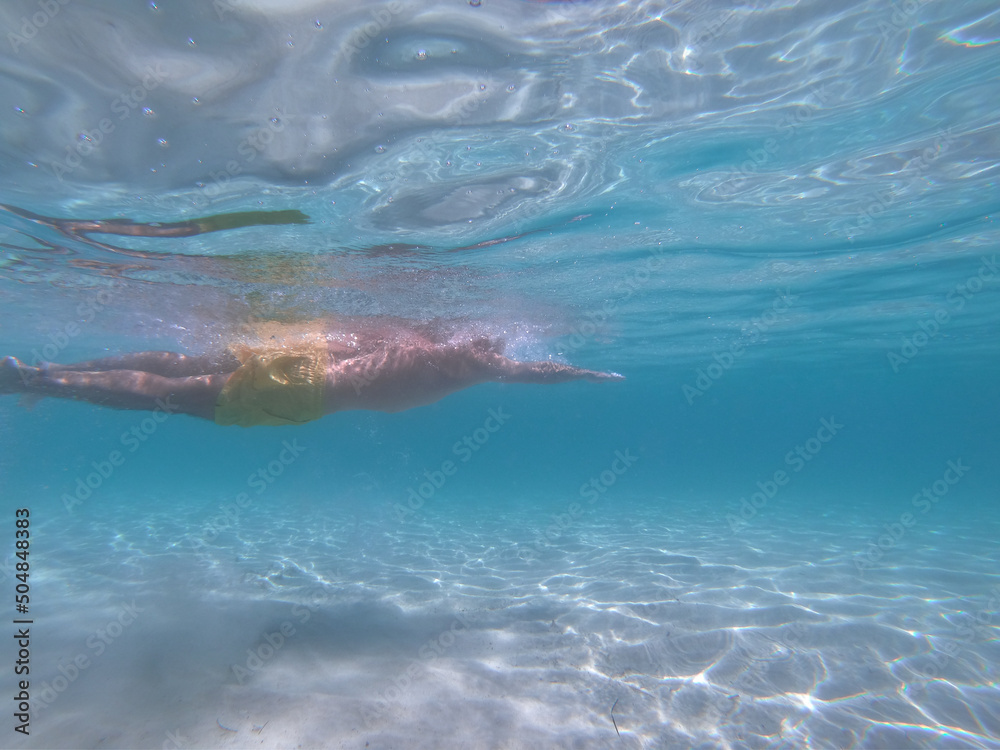 underwater scene of a man swimming crawl sltyle in a blue crystal clear watter beach. Concept of sport, holiday and travel.
