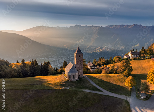 Hafling, Italy - Aerial view of the mountain church of St. Catherine (Chiesa di Santa Caterina) near Hafling - Avelengo on a warm autumn sunset with the Italian Dolomites in South Tyrol at background photo