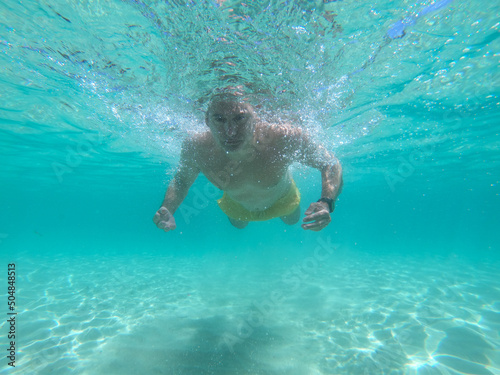 underwater scene of a man swimming and floating in a blue crystal clear watter beach. Concept of sport, holiday and travel. 