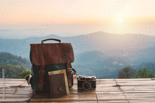 Travel backpack and retro camera with landscape view of mountain at sunrise