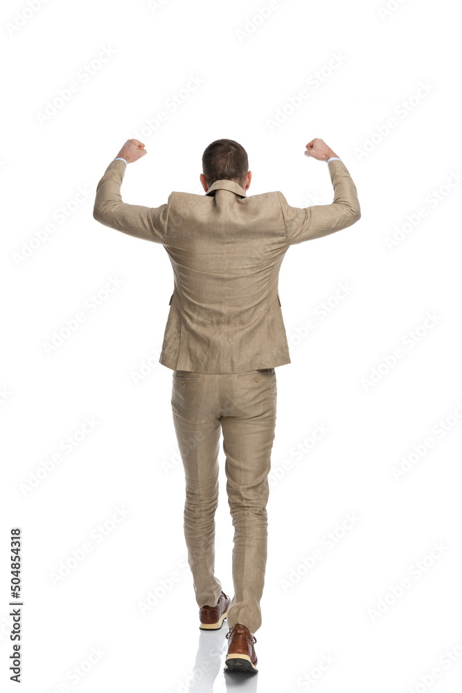 back view of businessman in beige suit holding arms in the air back view of businessman in beige suit holding arms in the air