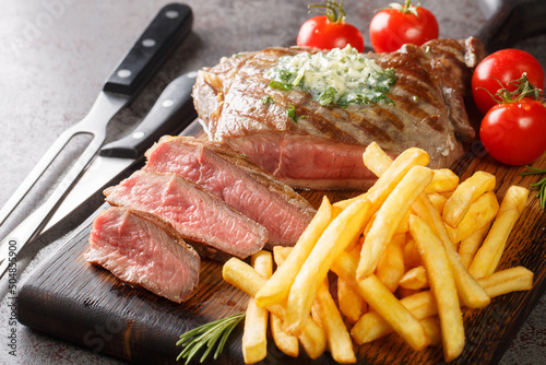 Steak Frites with lemon herb butter is a classic French dish closeup on the wooden board on the table. Horizontal