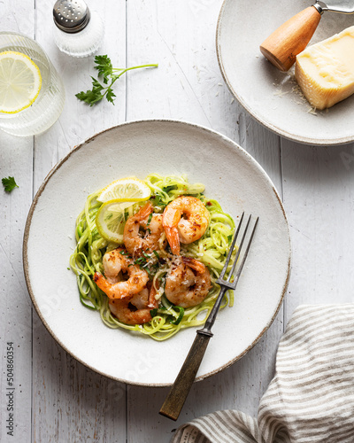 Zucchini pasta with shrimps on white wooden background, top view 