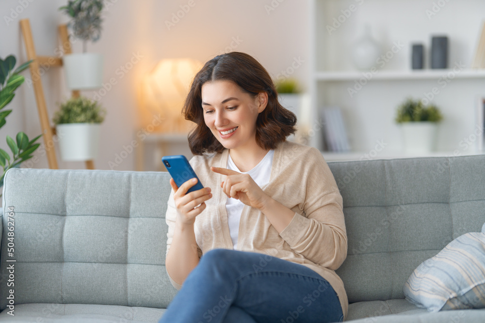 woman is using a phone sitting on a sofa woman is using a phone sitting on a sofa