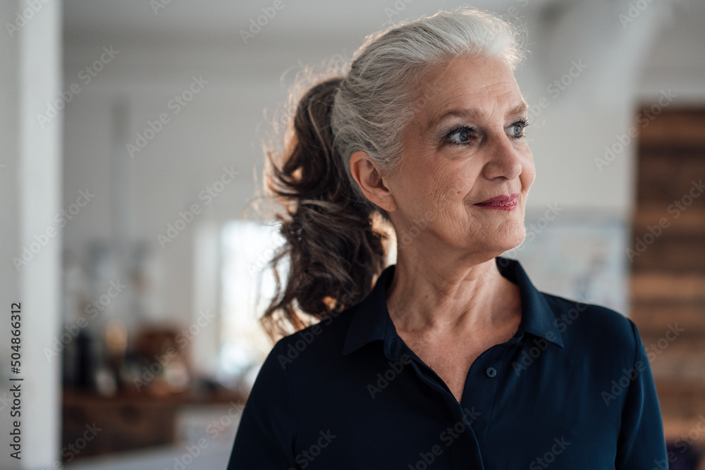 Thoughtful smiling businesswoman with gray hair in office